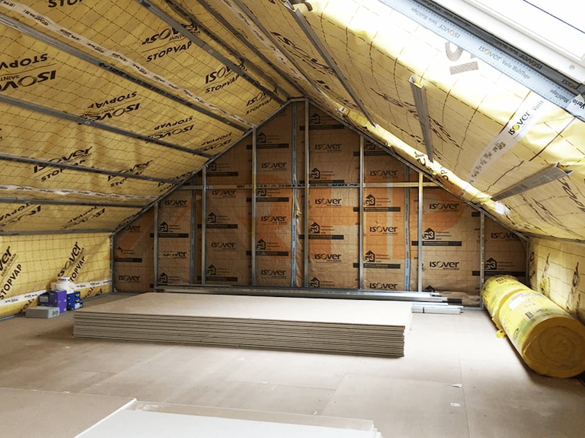 Chantier d'isolation de combles aménageables sous rampants — laine de verre Isover entre chevrons, pare-vapeur et plaques de plâtre