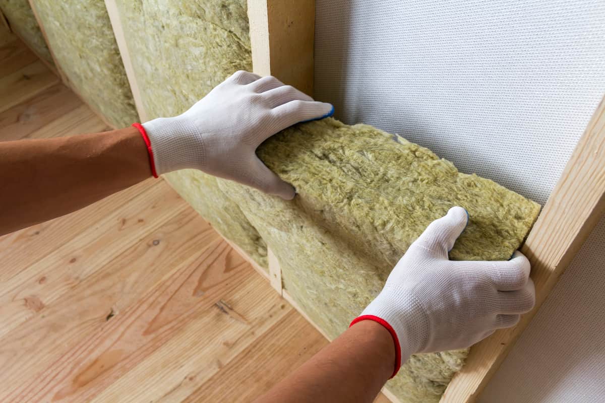 Pose de panneaux de laine de roche entre montants en bois pour isolation thermique d'un mur intérieur — résistance thermique R ≥ 3,7