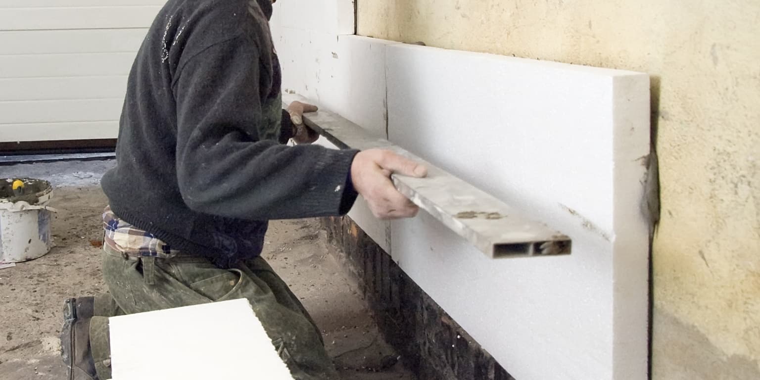 Pose de panneaux de polystyrène expansé (PSE) blancs sur mur intérieur existant pour isolation thermique
