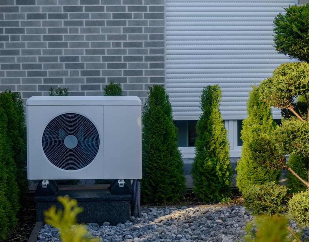 Unité extérieure d'une pompe à chaleur hybride installée sur le mur d'une maison