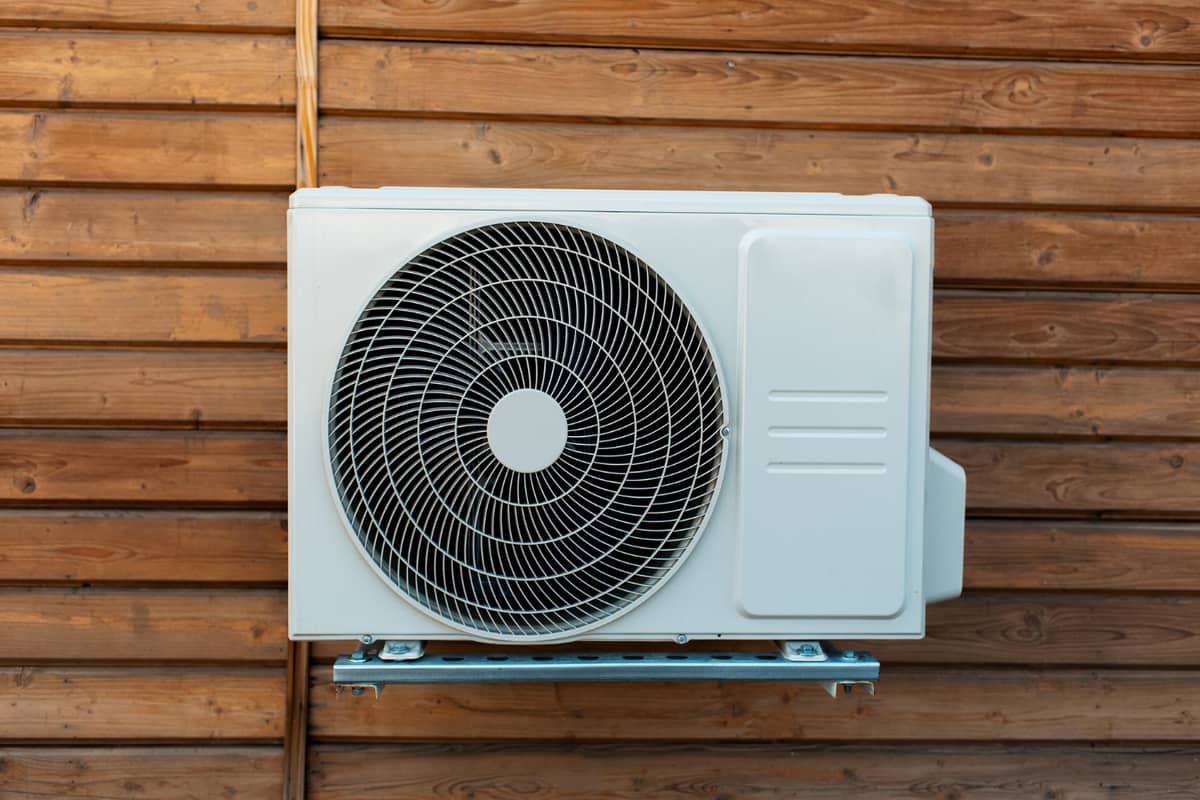 Unité extérieure compacte d'une pompe à chaleur air-air fixée sur un bardage en bois — petite puissance pour maison individuelle