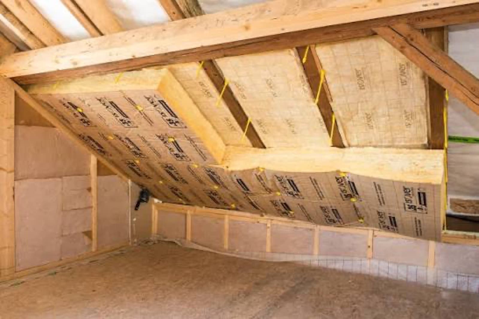 Rampant de toiture fraîchement isolé avec des panneaux à parement kraft entre les chevrons, comble aménagé en cours de rénovation