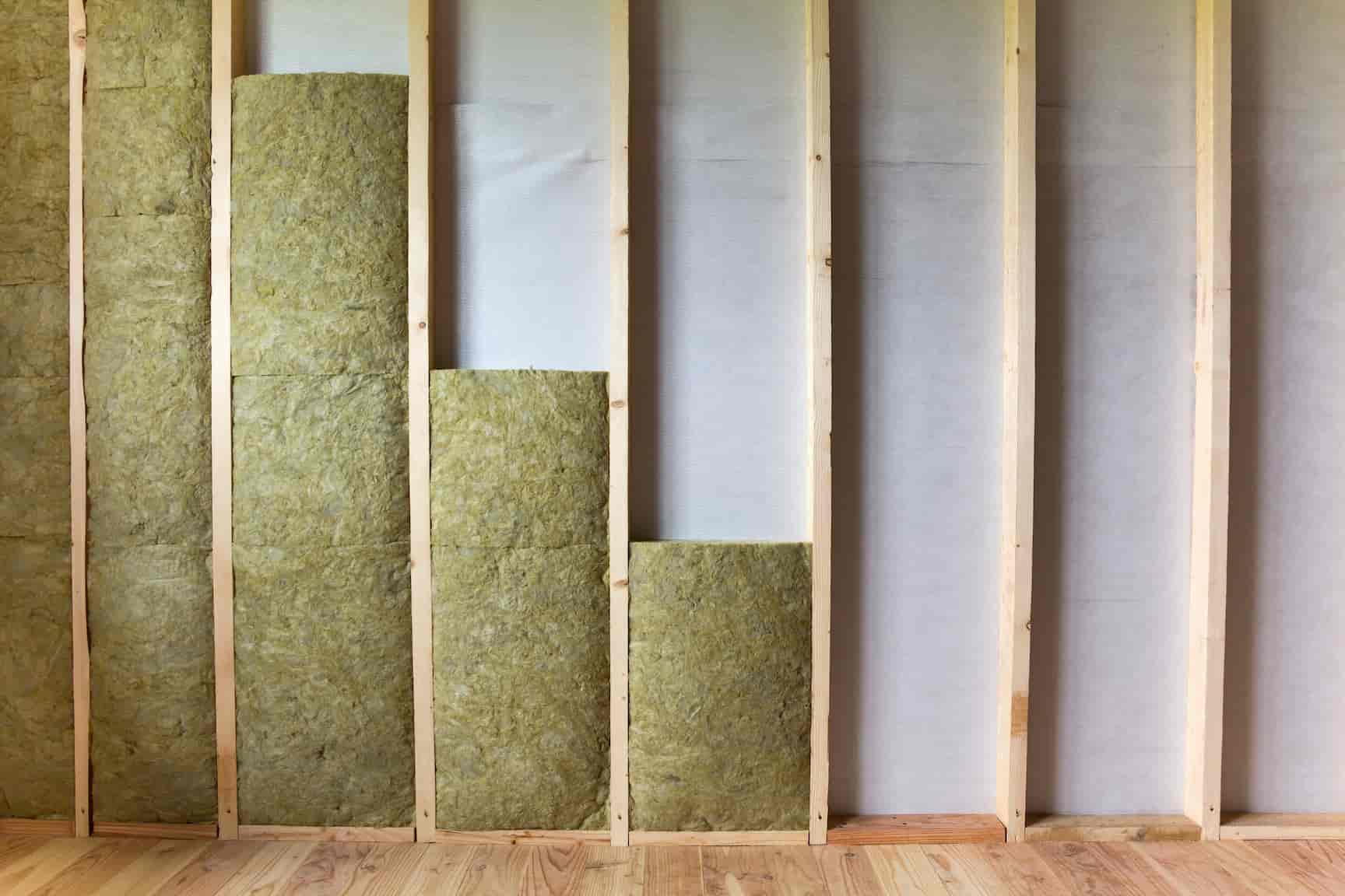 Panneaux de laine de roche installés entre montants en bois avec pare-vapeur gris visible à droite