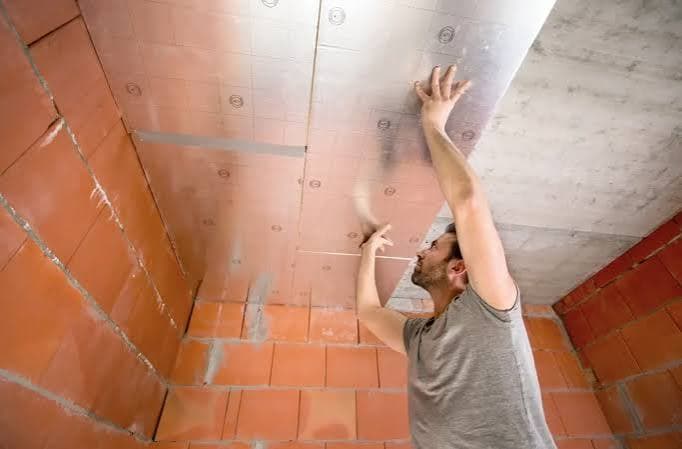 Pose de panneaux isolants avec parement aluminium formant un pare-vapeur au plafond d'une cave carrelée