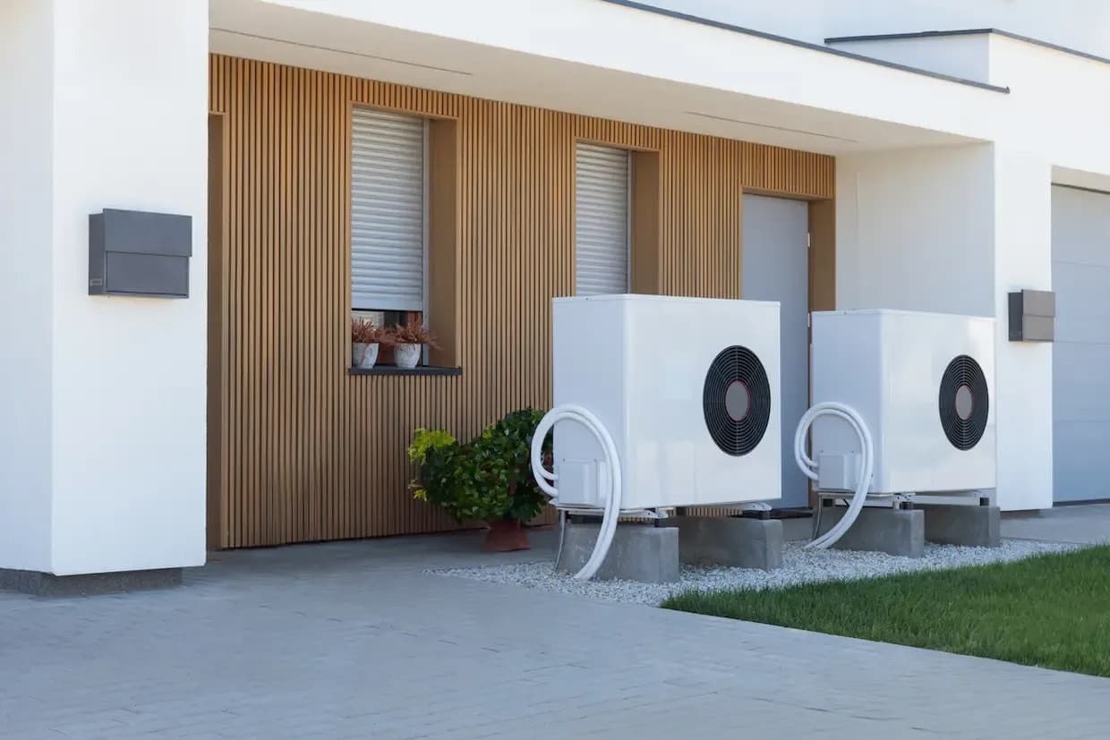Deux unités extérieures de pompe à chaleur air-eau posées sur socles devant une maison moderne à bardage bois — note de dimensionnement pompe à chaleur