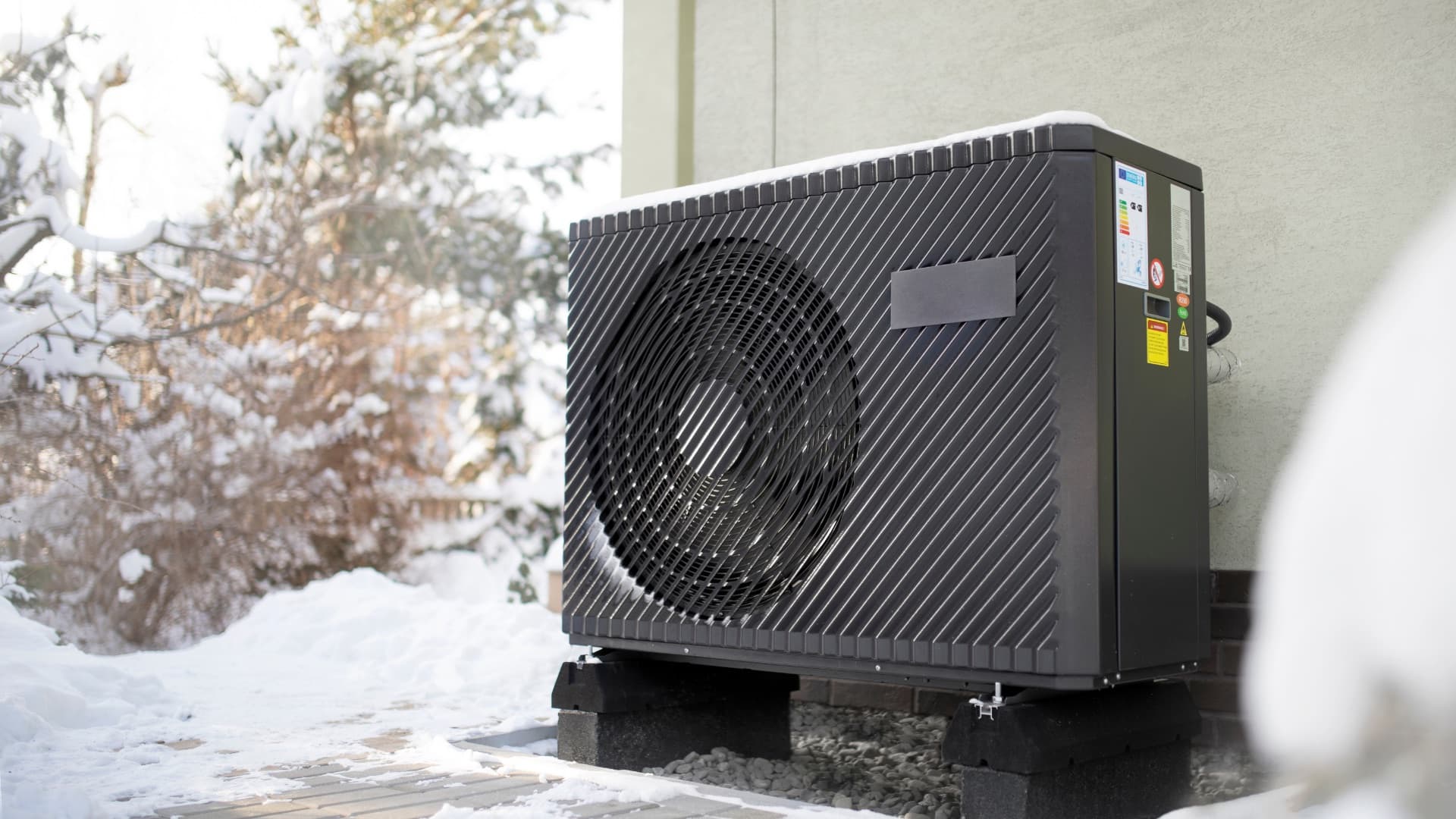 Pompe à chaleur installée à l'extérieur, recouverte de neige en plein hiver — la durée de vie d'une pompe à chaleur dépend de sa résistance aux conditions climatiques
