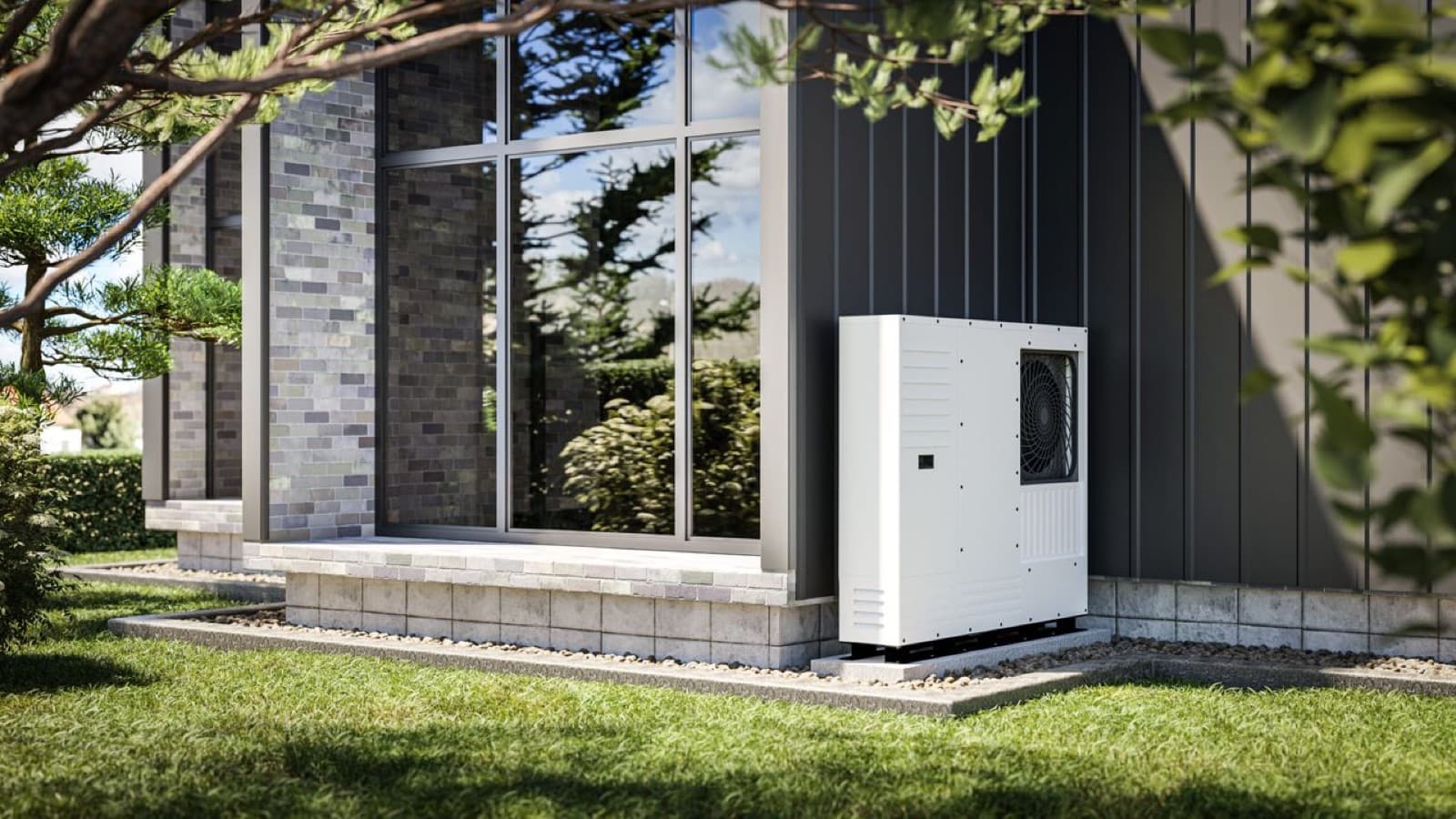 Unité extérieure blanche d'une pompe à chaleur air-eau installée contre le mur d'une maison moderne au bardage sombre, entourée de végétation