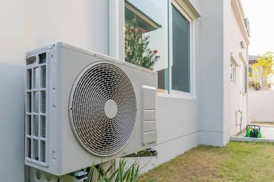 Unité extérieure de pompe à chaleur installée près d'une fenêtre, illustrant l'importance de l'emplacement pour la tranquillité du voisinage