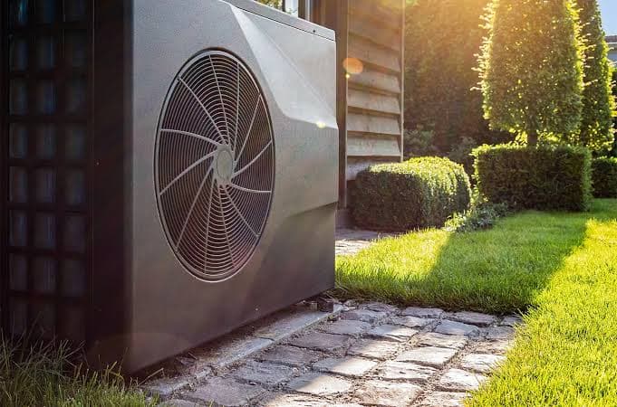 Gros plan sur le ventilateur d'une unité extérieure de pompe à chaleur dans un jardin, source principale du bruit ambiant perçu